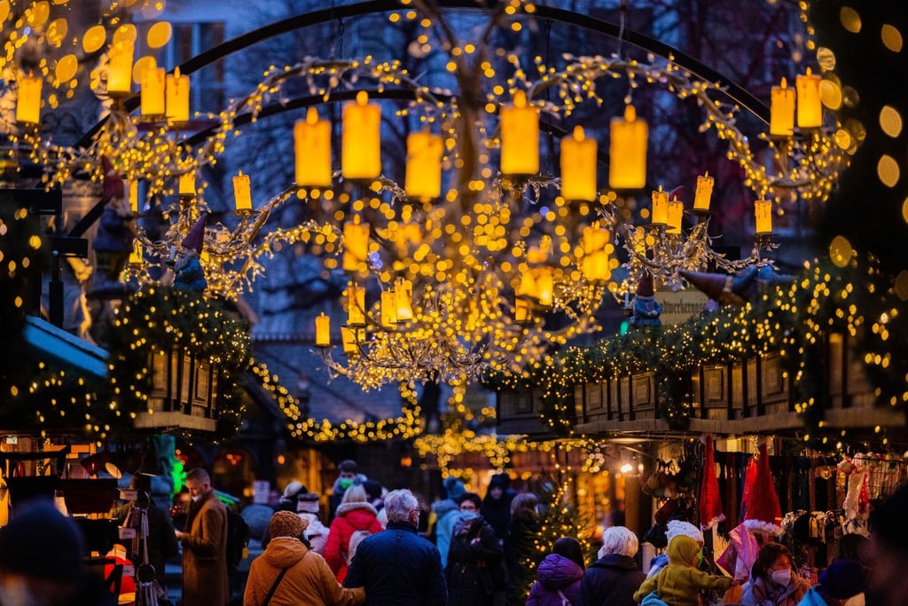 Besucher gehen über einen Weihnachtsmarkt.