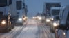 Fahrzeuge fahren Stop-and-go bei Schneefall auf einer Autobahn.