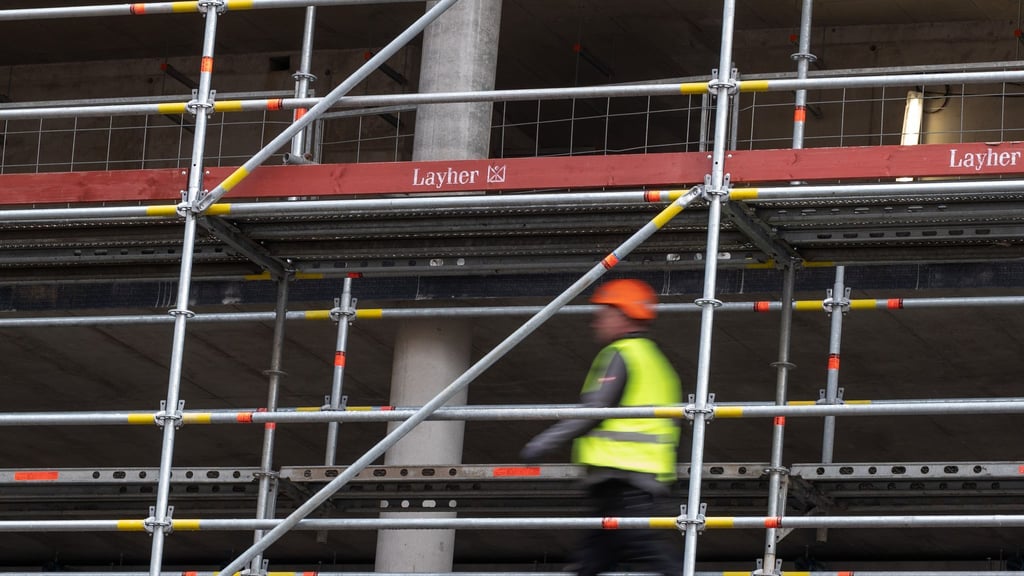 Ein Bauarbeiter geht über ein Baustellengerüst.