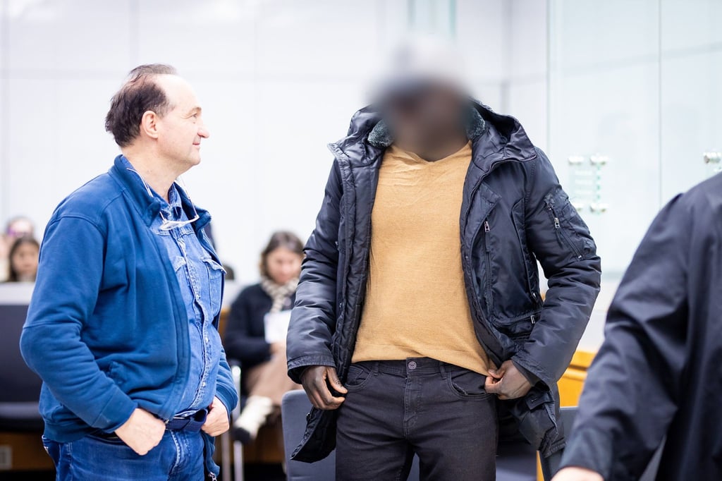 Der Angeklagte (r) steht im Gerichtssaal.