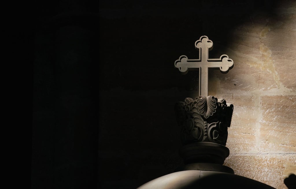 Ein Lichtstrahl fällt in einer Kirche auf ein Kreuz.