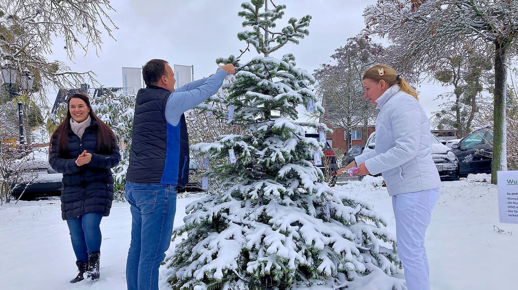 Gemeinsam mit einer Mitarbeiterin des Coswiger Seniorenparks putzen Nicole Riedel (li.) und Michel Hömke (Mitte) den Wunschbaum.