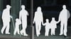 Figuren von Menschen in verschiedenem Alter sind auf Fensterscheiben aufgeklebt.