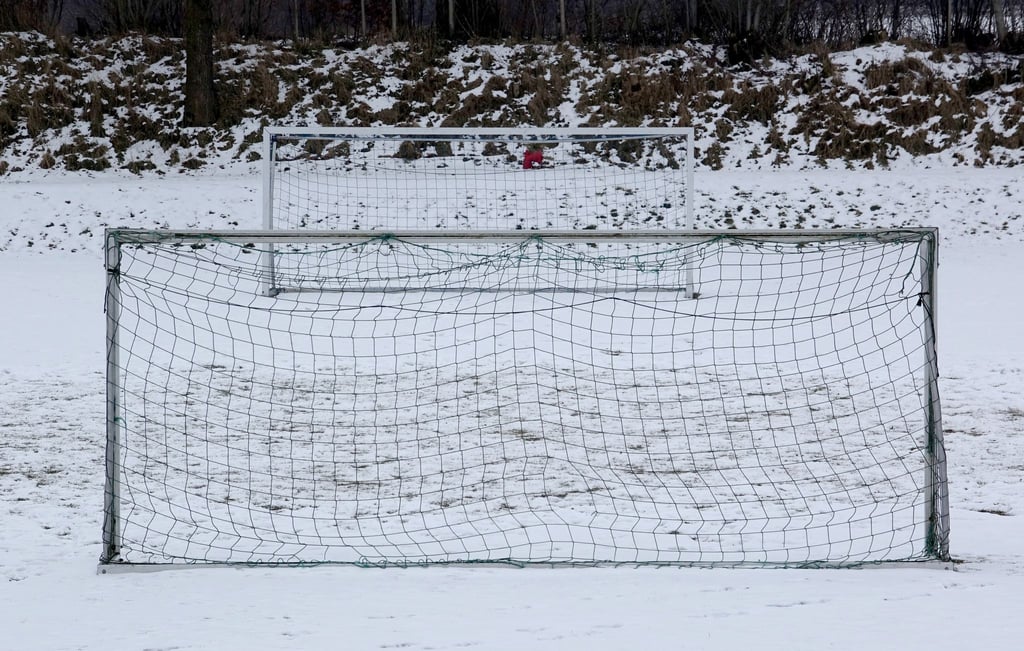 Fußballtore stehen auf einem schneebedeckten Fußballplatz.