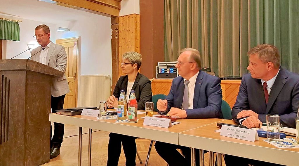 Ministerpräsident Reiner Haseloff (M.) folgt dem Bericht von Bürgermeister Peter Müller (l.) in der Einwohnerversammlung im Rathaus von Zahna .