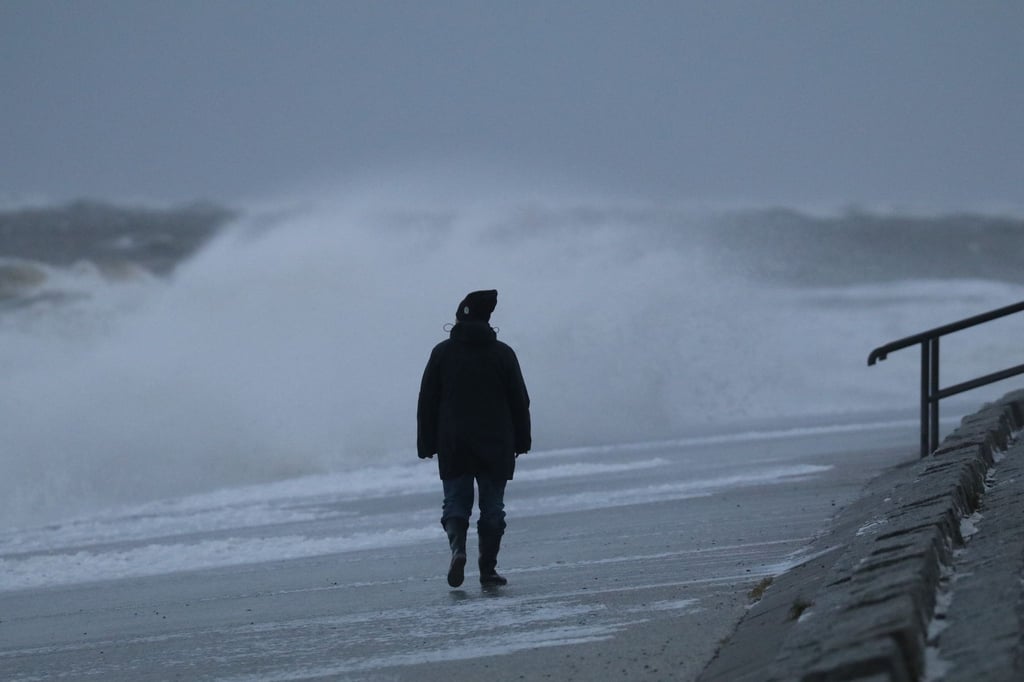 Eine Spaziergängerin läuft bei stürmischem Wetter am Nordstrand der ostfriesischen Insel Norderney.