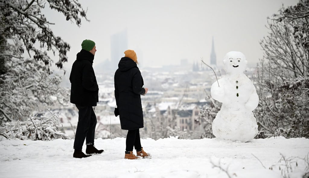 Zwei Spaziergänger wandern am Fockeberg (Leipzig) an einem Schneemann vorbei.