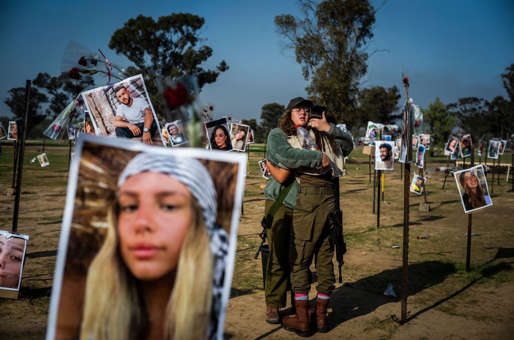 Israelische Soldatinnen stehen zwischen Fotos getöteter Israelis am Ort des Massakers beim Re'im-Musikfestival in der Negev-Wüste.