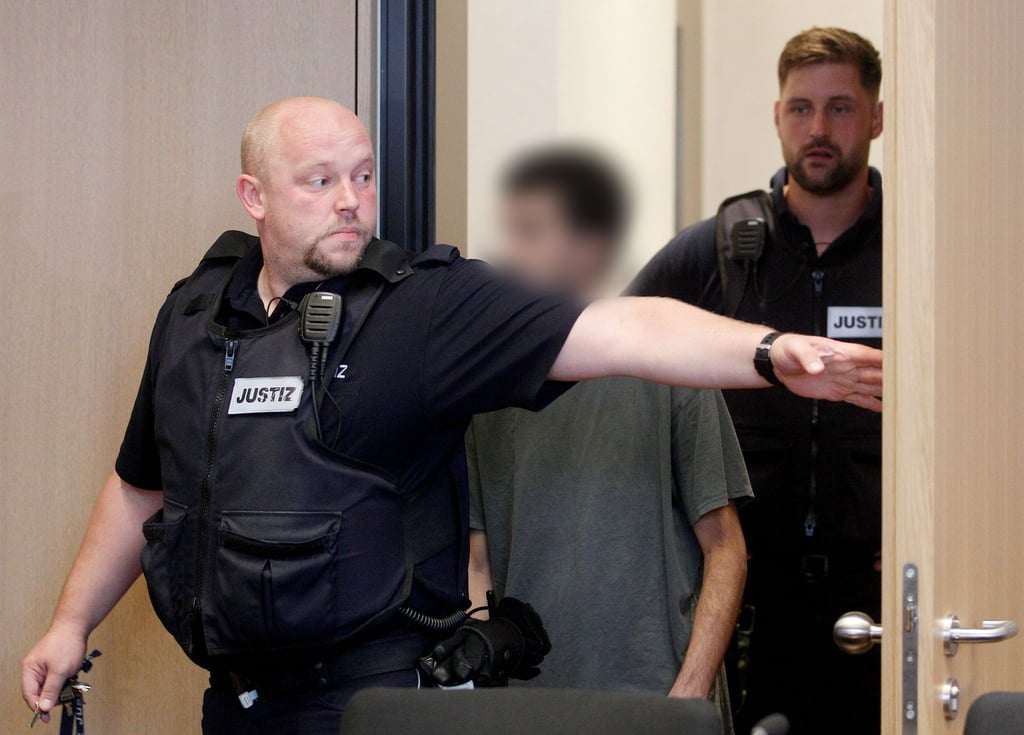 Der Hauptangeklagte wird von Justizbeamten in den Gerichtssaal geführt.