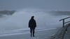 Eine Spaziergängerin läuft bei stürmischem Wetter am Nordstrand der ostfriesischen Insel Norderney.