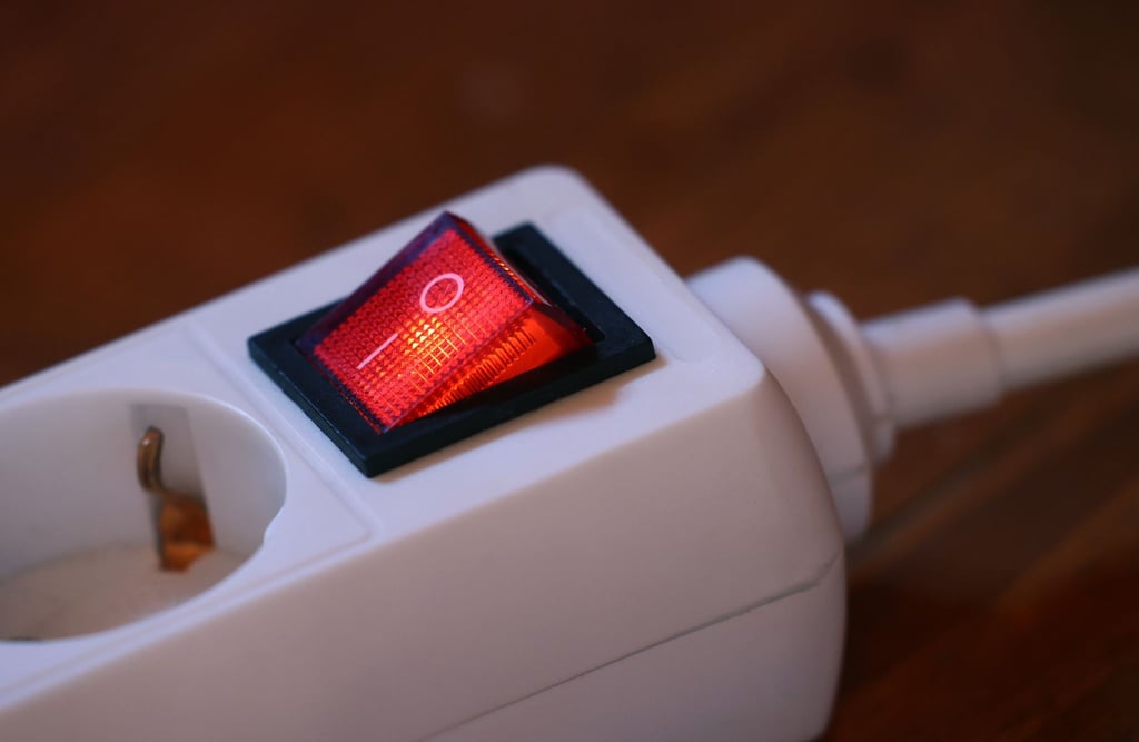 Der eingeschaltete Schutzschalter einer Mehrfachsteckdose leuchtet rot.