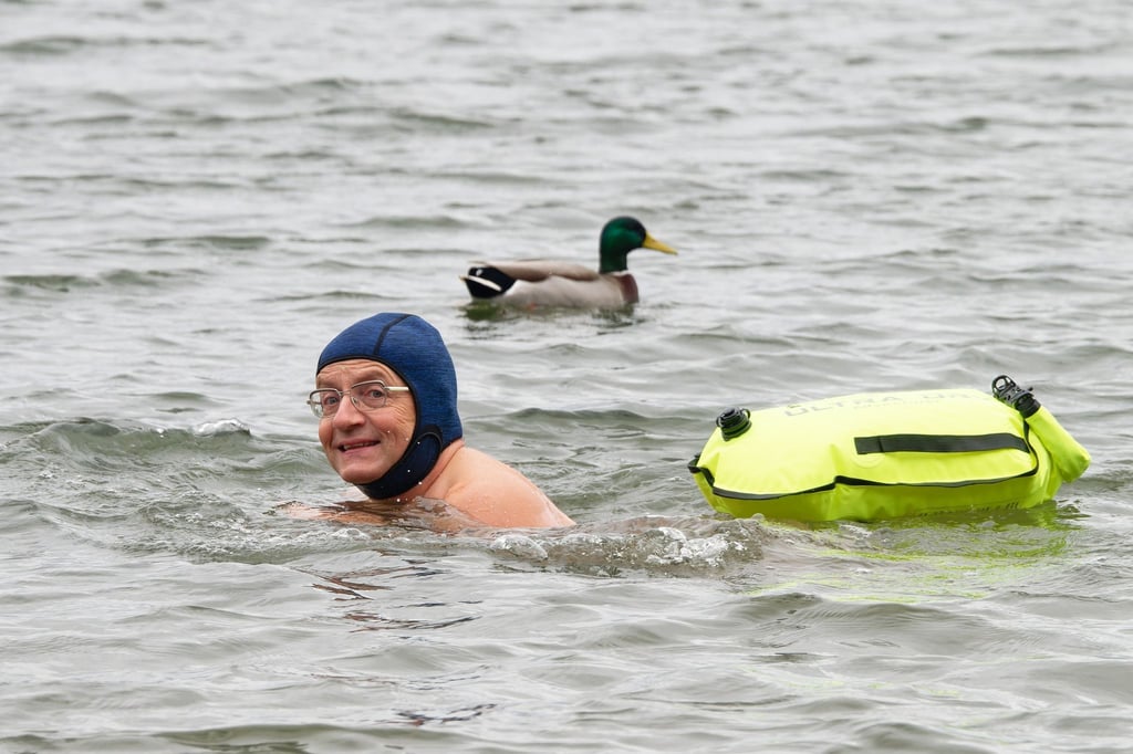 Comedian Wigald Boning schwimmt neben einer Ente in einem See.