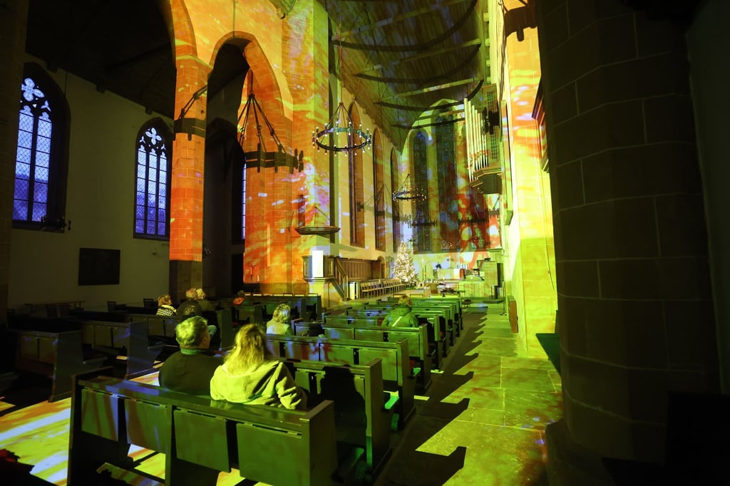 Besucher betrachten Lichtkunst in der Evangelischen Augustinerkirche zu Erfurt.