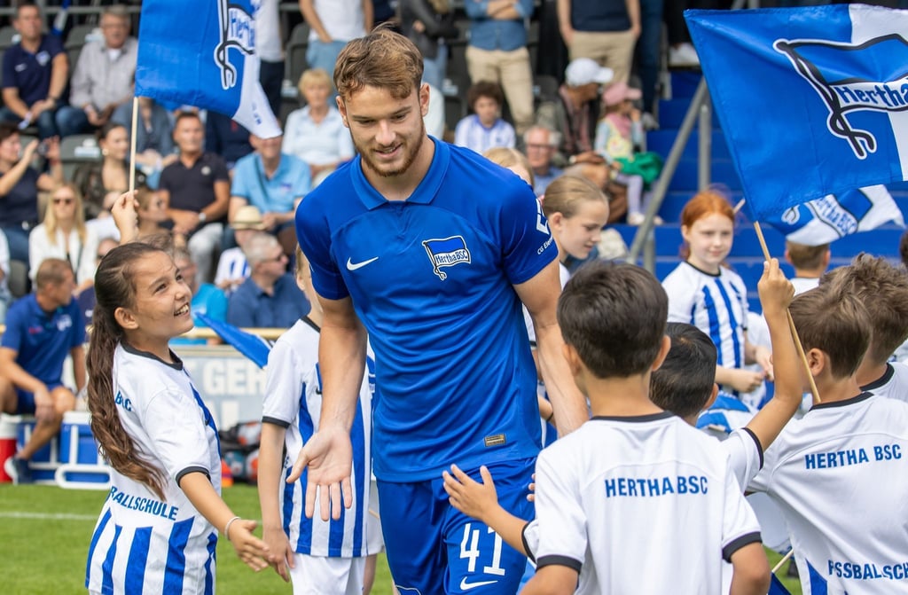 Pascal Klemens begrüßt lächelnd Fans und Kinder auf dem Übungsplatz.