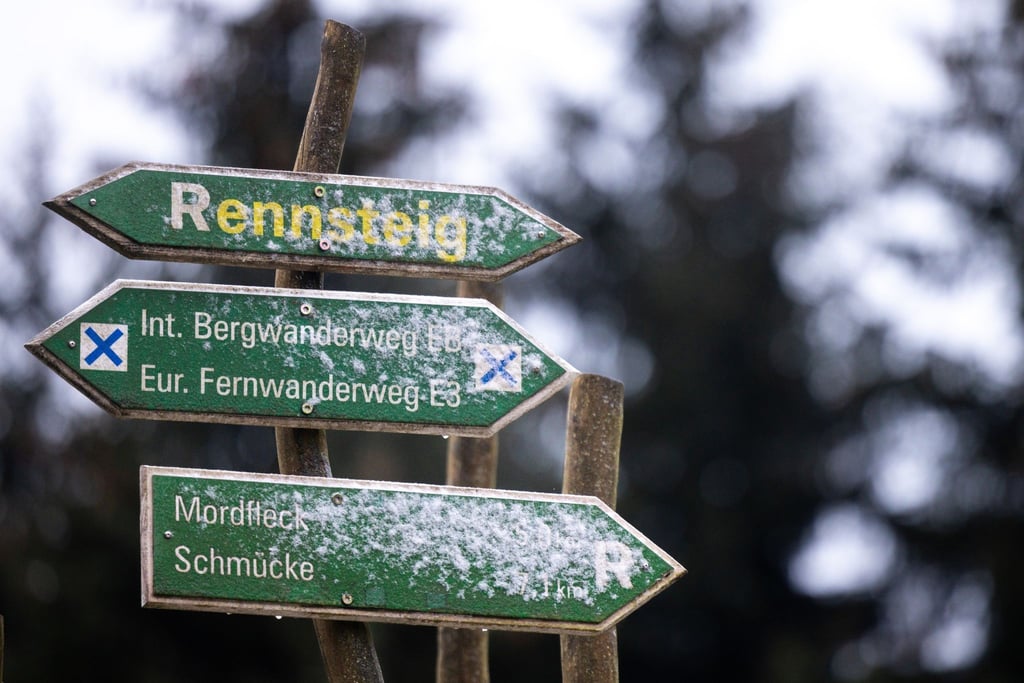 Ein Wegweiser am Höhenwanderweg Rennsteig ist mit einer dünnen Schneeschicht überzogen.