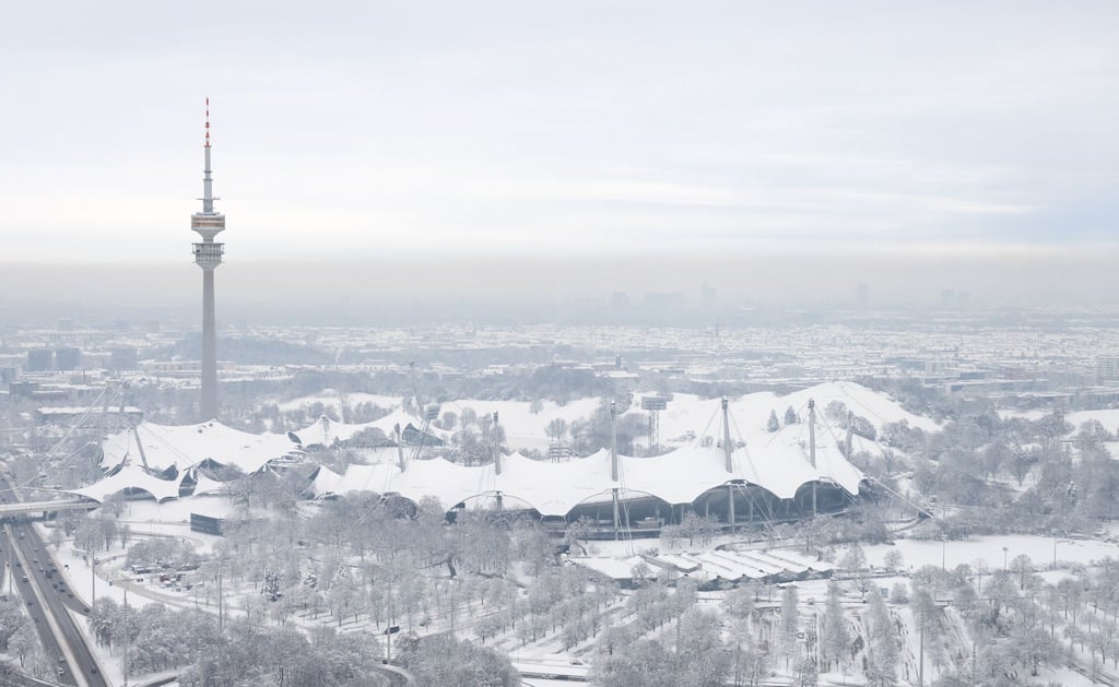 Der schneebedeckte Olympiapark mit dem Olympiaturm ist von einem Hochhaus zu sehen.