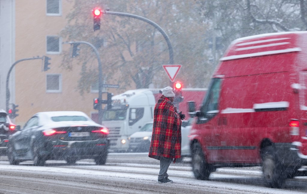 Zwischen wartenden Autos an der Ampel: Bitte um Almosen bei Schneetreiben in Hamburg.