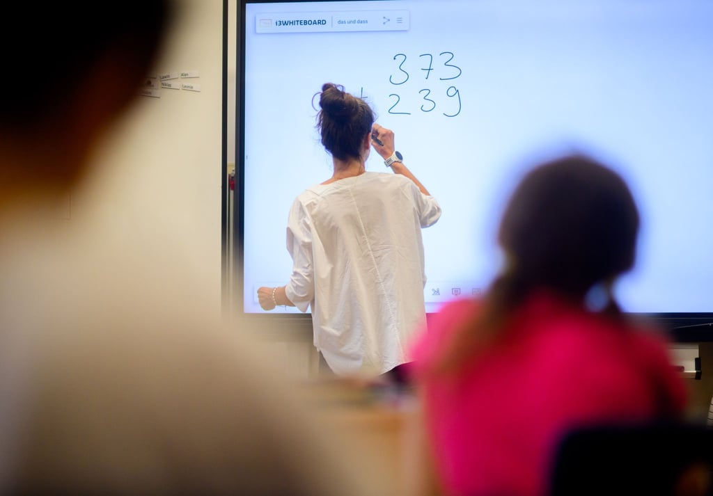 Ein Lehrerin schreibt Mathematikaufgabe auf eine digitale Tafel.