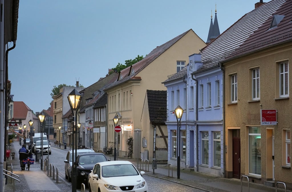 Ein Zeitungszusteller schiebt am frühen Morgen sein Fahrrad auf dem Fußweg in Richtung Marktplatz.