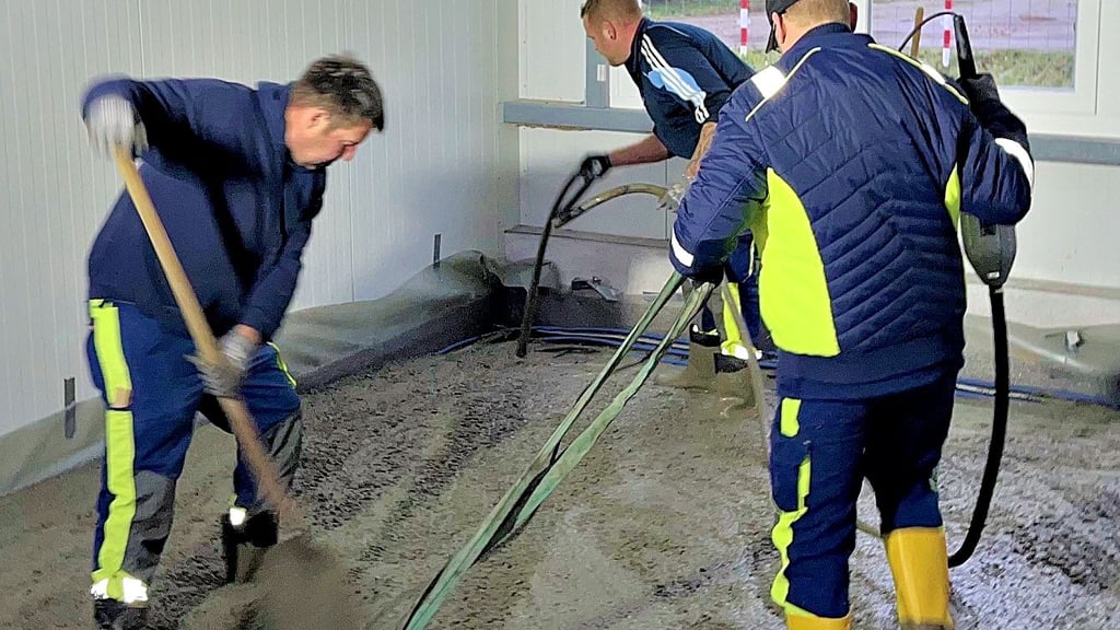 Mitarbeiter des Bauhofes bringen Estrich in der „Warmen Halle“ des neuen Bauhofes auf.