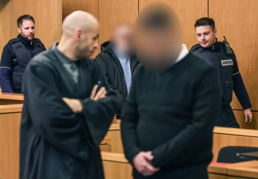 Die Angeklagten werden von Justizbeamten in den Gerichtssaal geführt.
