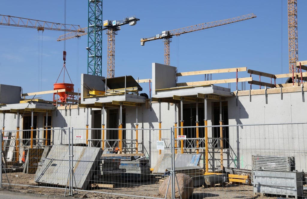 Kräne und Gerüste stehen auf der Baustelle eines Mehrfamilienhauses.
