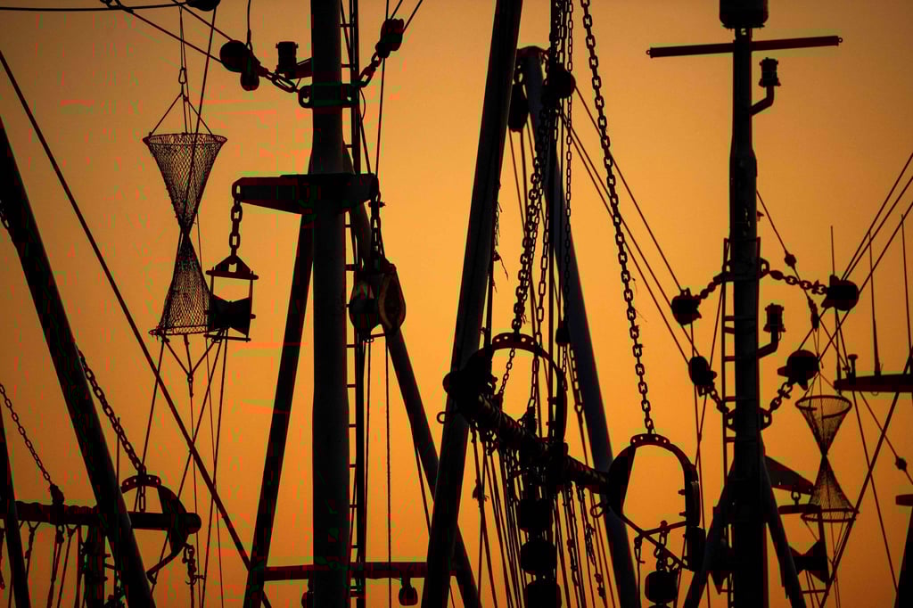 Krabbenkutter liegen bei Sonnenuntergang im Hafen.