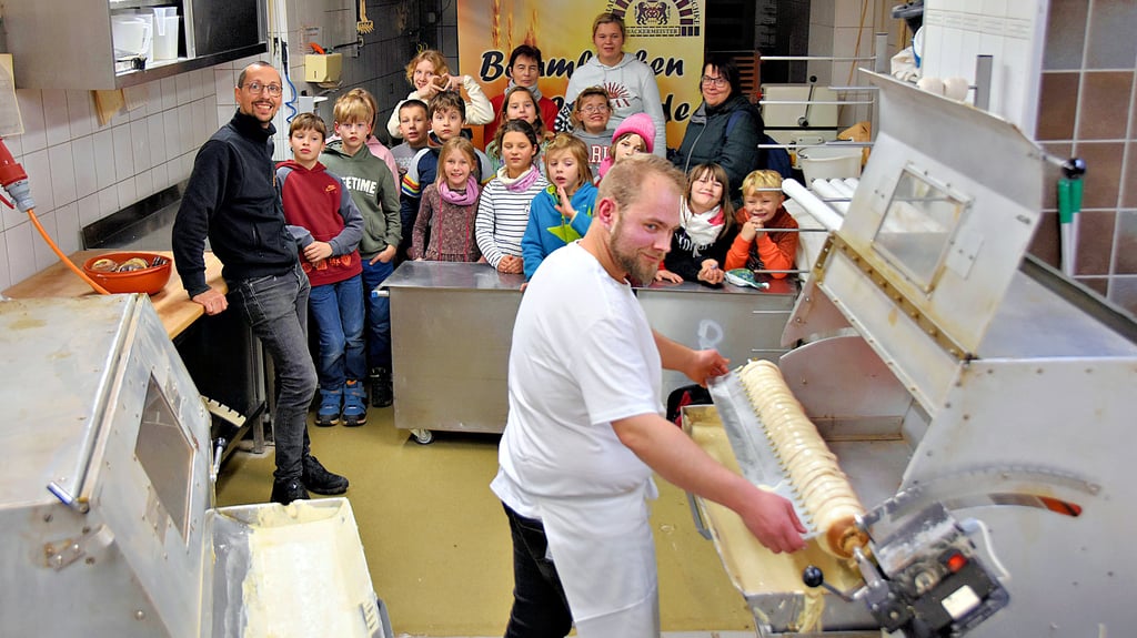 Nach dem Eintauchen wird der Baumkuchen gekämmt. Konditor Oliver Körner zeigt in der Backstube, wie ein Baumkuchen Schicht für Schicht gebacken wird. Bäckermeister Denni Nitzschke (l.) begrüßt Kinder der Evangelischen Grundschule Gardelegen. „Die Backaktion zählt zum Lebendigen Adventskalender“, erklärt Sabine Wieter (hinten; links), Mitarbeiterin der Biosphärenreservats Drömling.