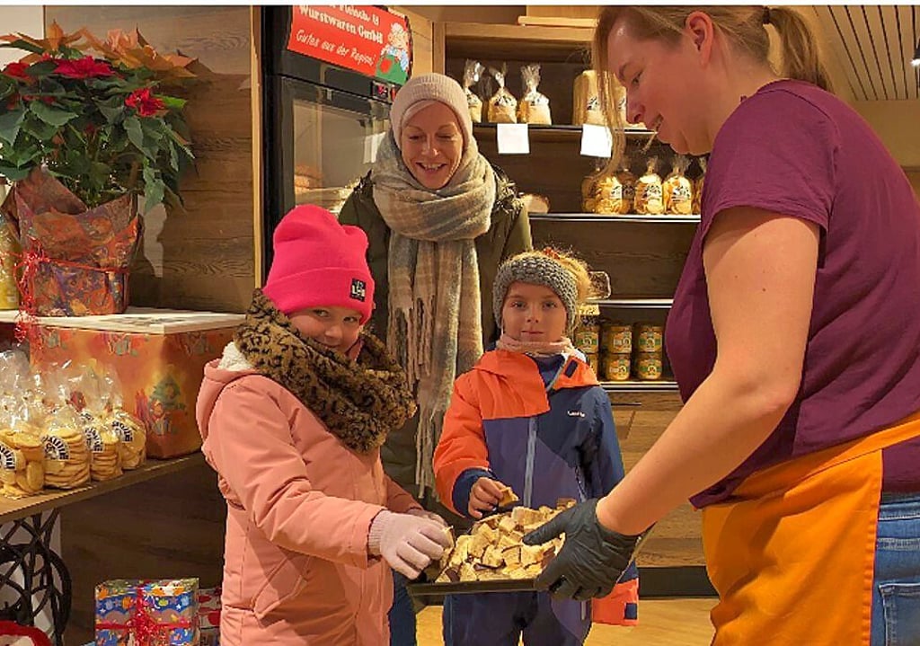 Verkäuferin Anja Vorreier verteilt Kostproben verschiedene Baumkuchensorten auch an Anne Wenzel mit Tochter Enni und deren Freundin Zoe.