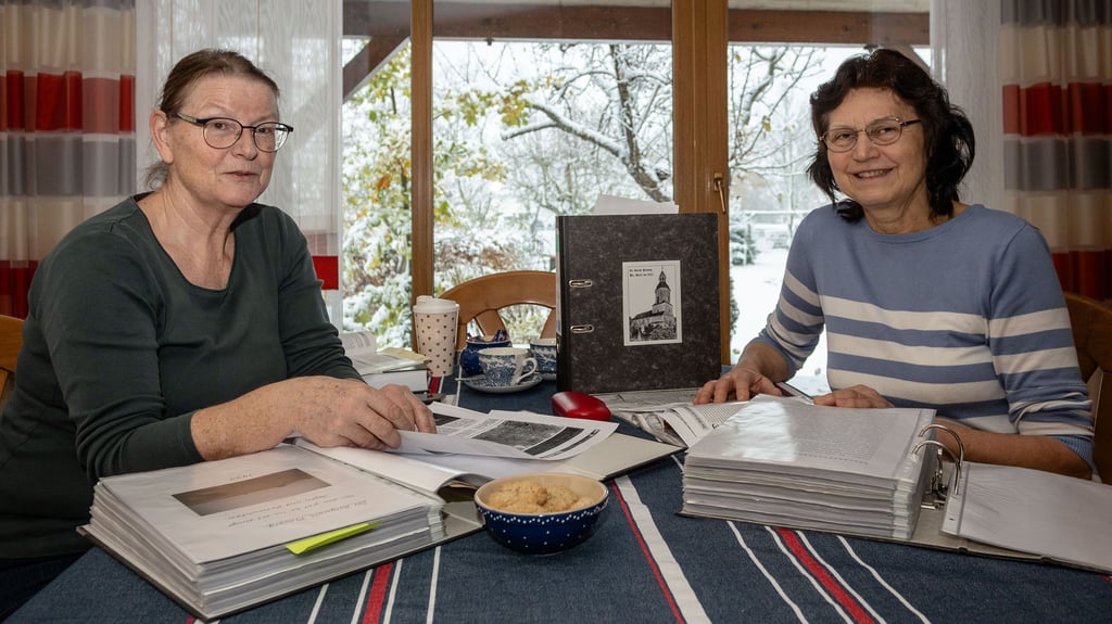 Anna Seidel (l.) und Heidrun Lindner forschen in der Ortschronik zum Namen des Dorfes Plossig.