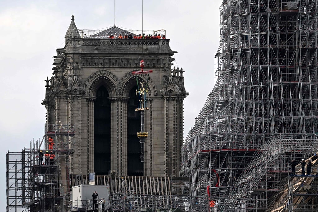 Das Kreuz der Kathedrale Notre-Dame wird während des Wiederaufbaus auf die neu errichteten Turmspitze gesetzt.