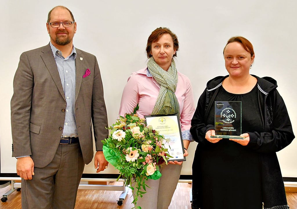 Landrat Martin Stichnoth übergibt die Auszeichnung für familienfreundliche Arbeitgeber an Nicole Olms (Mitte) und Stefanie Richter von der Lebenshilfe Ostfalen.