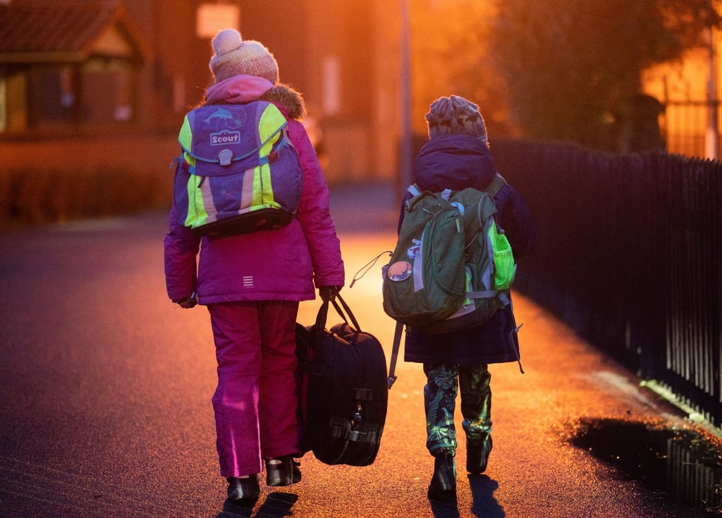Zwei Schüler gehen am frühen Morgen auf dem Schulweg zu ihrer Grundschule in der Region Hannover.