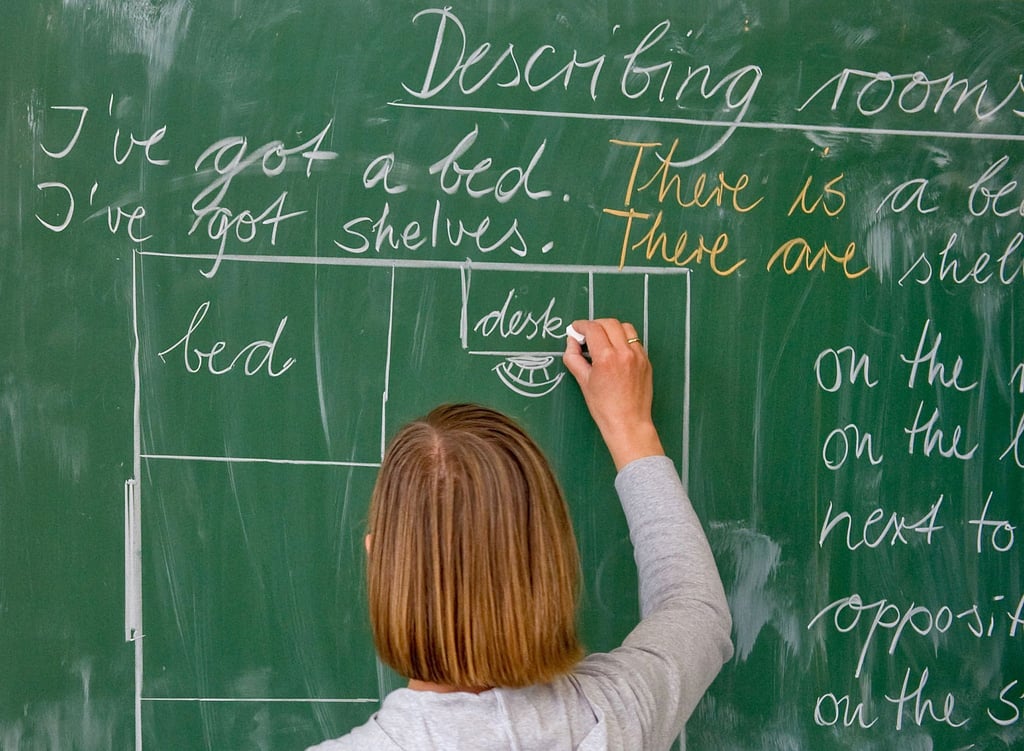 Eine Lehrerin einer Grundschule schreibt an die Tafel.