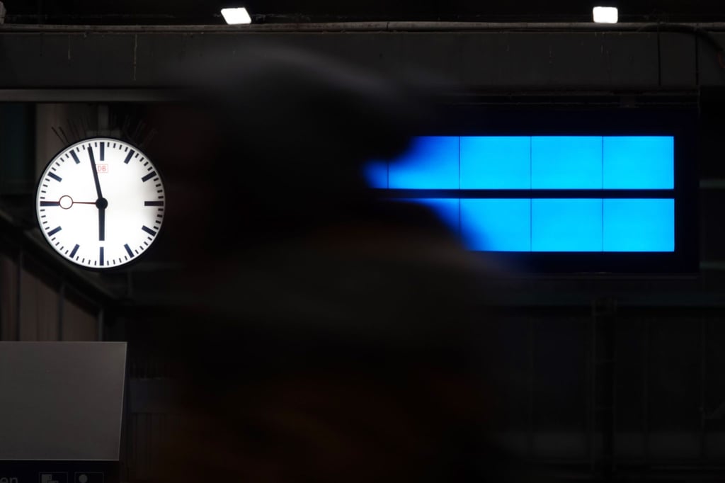 Ein Reisender steht vor einer leeren Anzeigetafel in einem Bahnhof.