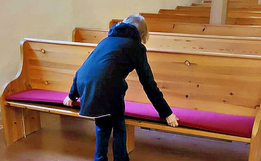 Sonja Teutschbein vom Gemeindekirchenrat legt die neuen Polster auf die Kirchenbänke.