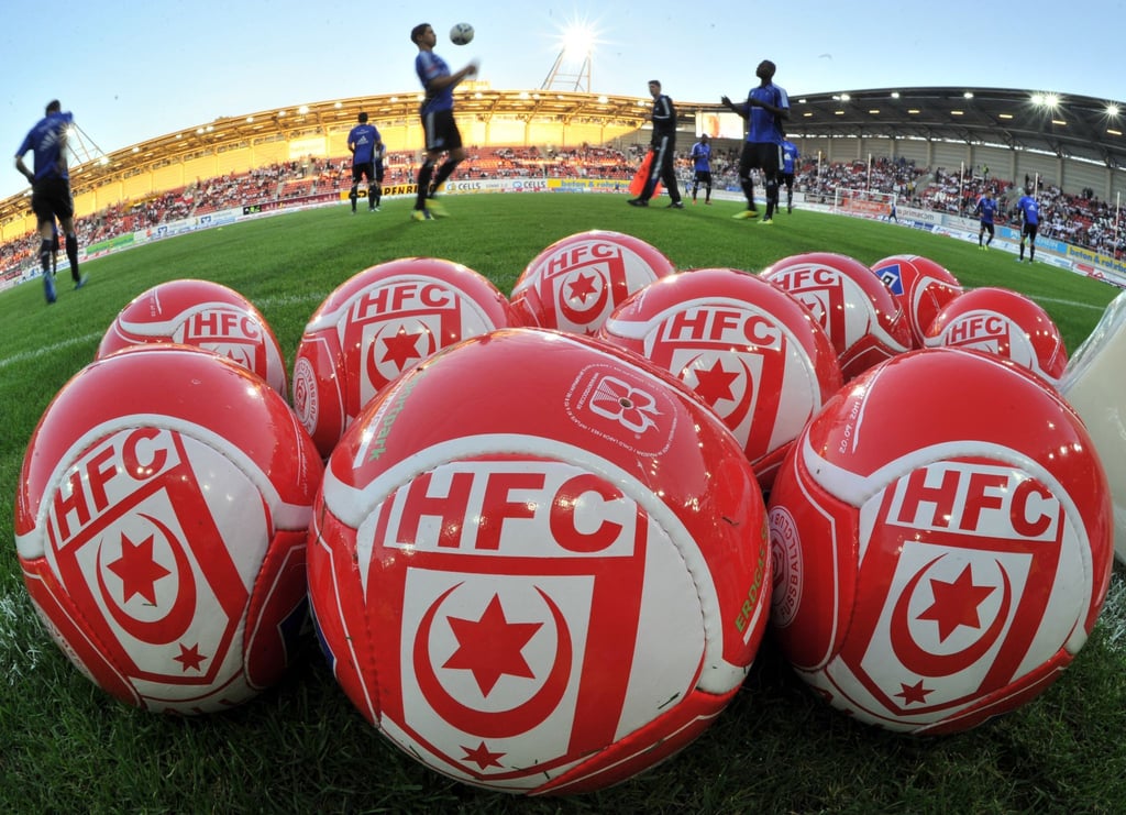 Fußbälle mit dem Logo des Halleschen FC liegen auf dem Rasen.