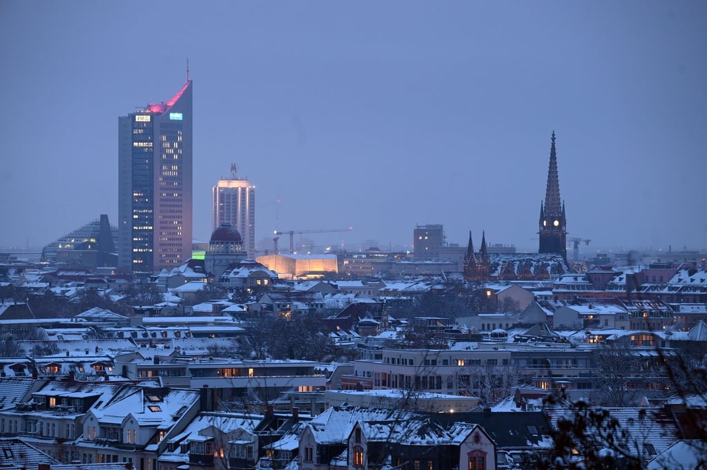 Schnee bedeckt abends die Dächer von Leipzig.