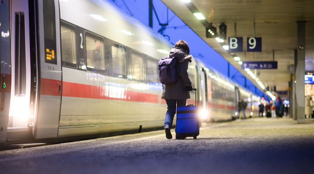Eine Frau geht mit einem Koffer neben einem ICE im Hauptbahnhof Hannover.