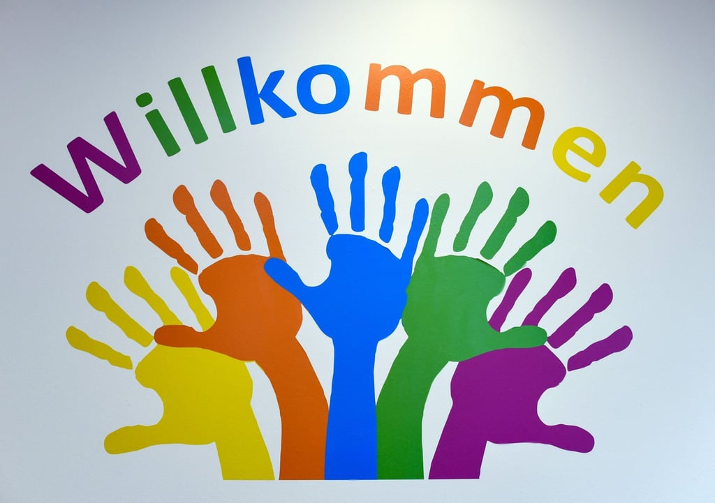 Bunte Hände und das Wort „Willkommen“ ziert eine Wand.