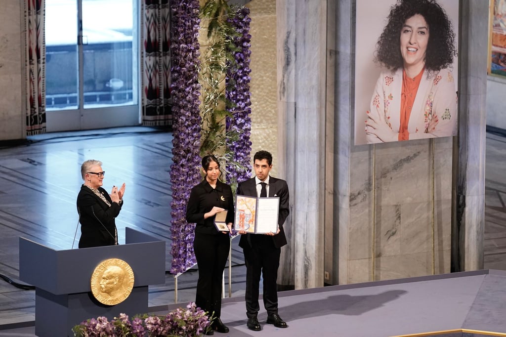 Kiana (l) und Ali Rahmani halten die Medaille und die Urkunde während der Verleihung des Friedensnobelpreises 2023 im Rathaus von Oslo. Die Zwillinge nehmen den Friedensnobelpreis stellvertretend für ihre inhaftierte Mutter entgegen.