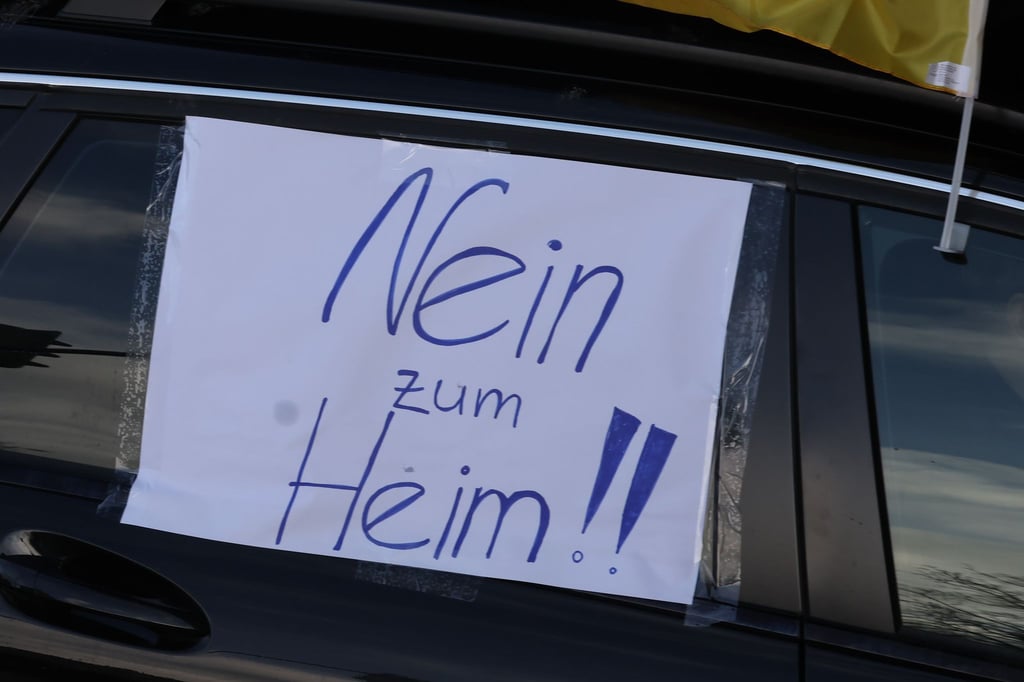 Ein Blatt Papier mit der Aufschrift "Nein zum Heim!!" hängt an einem Auto bei eines Autocorso durch die Innenstadt.