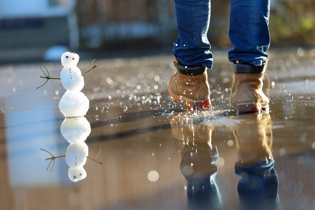 Ein kleiner Schneemann in einer Pfütze.