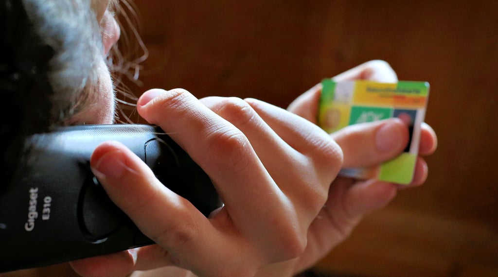 Ein Mann hält beim Telefonieren eine Gesundheitskarte in der Hand. Ob er wohl seinen Arzt anruft?