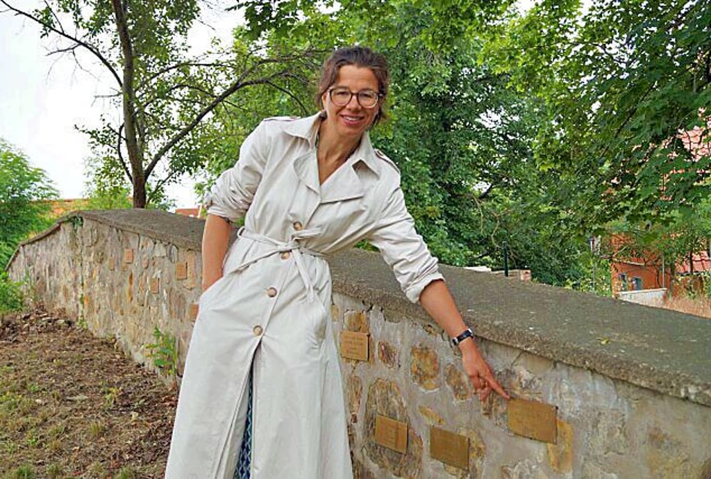 Maria Hufenreuter auf dem jüdischen Friedhof in Quedlinburg, wo Namenstafeln an der Mauer die jüdischen Bürger der Stadt erinnern, die deportiert und ermordert wurden oder selbst aus dem Leben schieden.