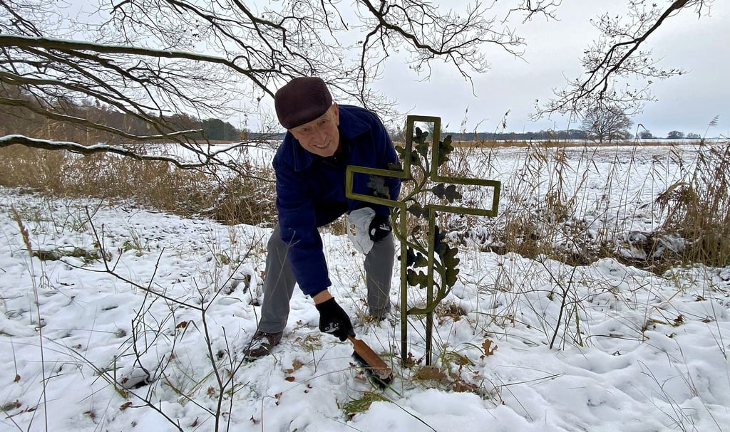 Der Hemsendorfer Baldur Waas befreit das schlichte Kreuz am alten Elsterarm vom Schnee. Hier soll einst der Gutsverwalter erschlagen worden sein.