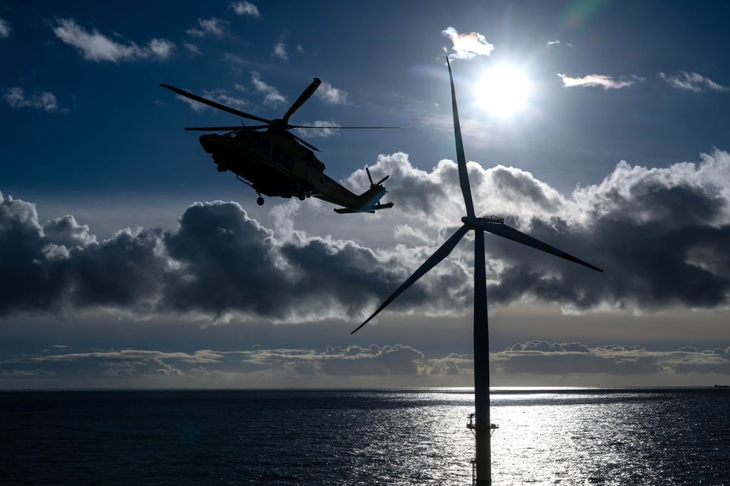 Ein Helikopter fliegt über einen Offshore-Windpark.