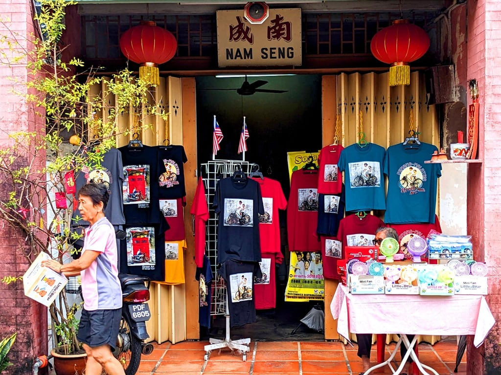 T-Shirts und andere Dinge, auf denen Street Art-Kunstwerke aus Penang abgebildet sind, werden in einem Geschäft zum Kauf angeboten.