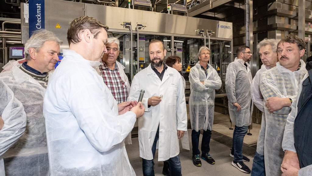 Roxane-Produktionsleiter Chris Heinke (M.) zeigt den Gewerbevereinsmitgliedern die hier in Jessen verwendeten Flaschenrohlinge.