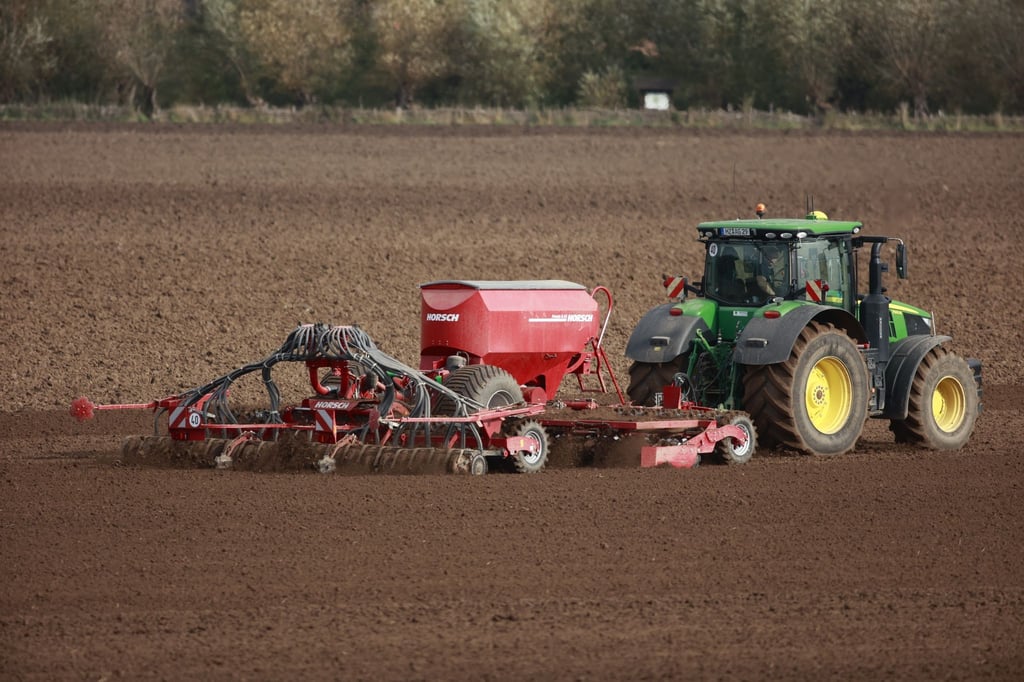 Ein Landwirt düngt mit einem Traktor sein Feld.